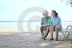 Elderly Asian couple holding laptops green screen on the beach