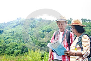 Elderly Asian couples traveling in the forest carrying maps