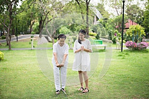 Elderly asian female exercise do physical with stick at park,Caretaker take care and support,Physical therapy