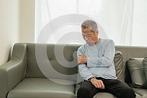 An elderly Asian male patient suffers from pain and numbness in his hand from rheumatoid arthritis.