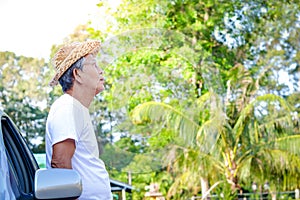 An elderly Asian man drives a car to travel