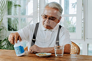 Elderly Asian man taking pill