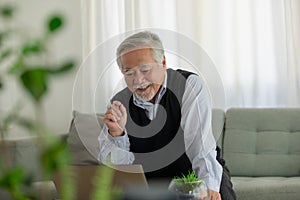 Elderly Asian man is working and note jobs on his laptop at home