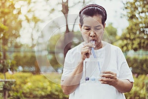 Elderly asian mother using incentive spirometer or three balls for stimulate lung at nature