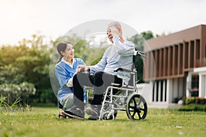 Elderly asian senior man on wheelchair with Asian careful caregiver. Nursing home hospital garden concept are walking in the