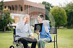 Elderly asian senior man on wheelchair with Asian careful caregiver. Nursing home hospital garden concept are walking in the