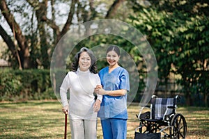 Elderly asian senior woman on wheelchair with Asian careful caregiver. Nursing home hospital garden concept