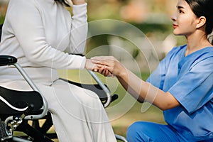 Elderly asian senior woman on wheelchair with Asian careful caregiver. Nursing home hospital garden concept