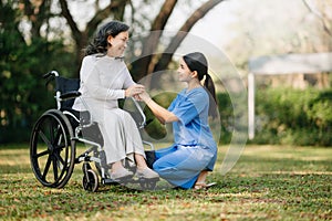 Elderly asian senior woman on wheelchair with Asian careful caregiver. Nursing home hospital garden concept. in sun light