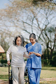 Elderly asian senior woman on wheelchair with Asian careful caregiver. Nursing home hospital garden concept