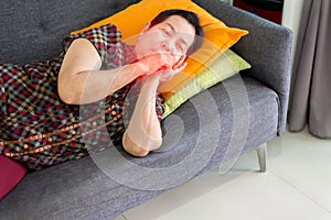 Elderly Asian woman coughing and lying on sofa at home,Female sore throat,Concept of health