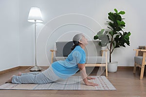 Elderly Asian woman exercising at home with yoga. Physical therapy.