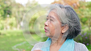 An elderly Asian woman exercising in an outdoor park in the morning.