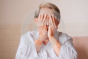 Elderly Asian woman with gray hair covering both eyes with hands, blindness, cataracts, pterygium, eye disease concept photo