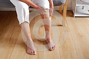 Elderly asian woman holding a leg that is painful from varicose veins or from osteoarthritis, Various illnesses of the elderly and