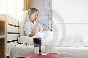 Elderly asian woman patient using incentive spirometer or three balls for stimulate lung in bedroom