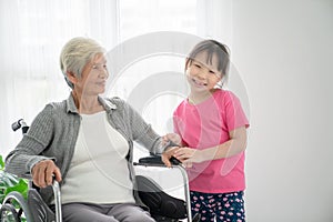 Elderly Asian woman sitting in wheelchair,sheâ€™s taking with her grandchild