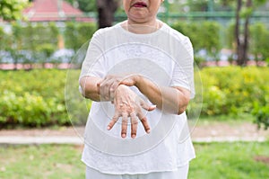 Elderly asian woman suffering with parkinson`s disease symptoms