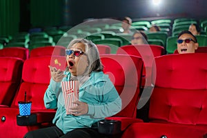 Elderly Asian Woman Surprised by Horror Film in Cinema