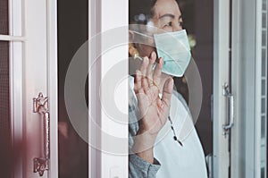 Elderly asian woman wearing face mask with hands touching on window,Stay at home during coronavirus and covid-19 epidemic or pande
