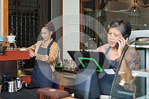 Elderly Asian woman who owns a coffee shop. Taking customer orders over the phone And tell the beautiful daughter barista to