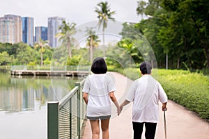 Elderly asian women standing and walking to do physical with stick at outdoor in the morning,Caretaker take care and support,Physi