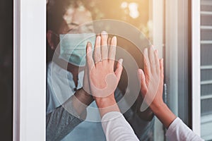 Elderly asian women wearing face mask with hands touching on window to people,Stay at home during coronavirus and covid-19 epidemi