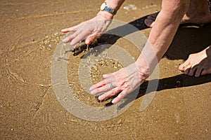 Elderly attractive woman touching the water on the seashore