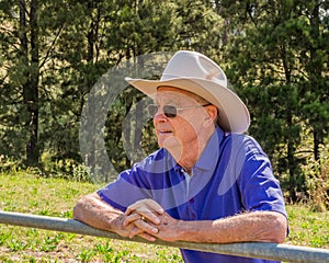 Elderly Australian farmer, looking over a fence into a paddock