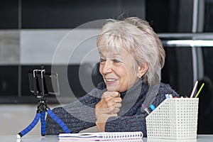 An elderly, beautiful woman in her 60s and 65s is video chatting, smiling happily.