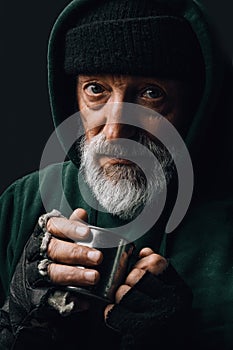 Elderly beggar being frozen outside, drinking hot water to get warm. Homeless. photo