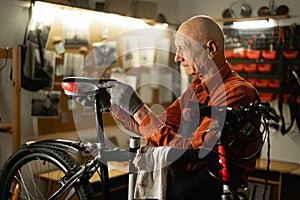 Elderly bicycle mechanic doing his professional work in workshop.