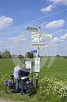 Elderly bikers reading road map in countryside