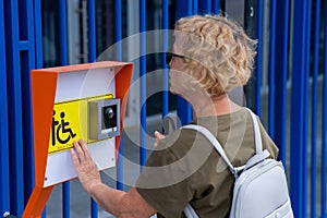 An elderly blind woman reading a text in braille. Button for calling help for people with disabilities.