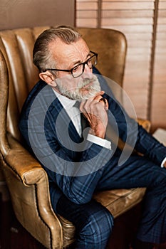 Elderly businessman in formal suit with whiskey and cigar at lux