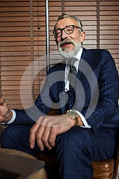 Elderly businessman in formal suit with whiskey and cigar at luxury interior