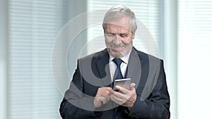Elderly businessman sending a text message.