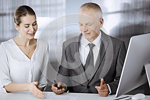 Elderly businessman and woman sitting and communicating in office. Adult business people or lawyers working together as