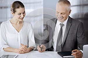 Elderly businessman and woman sitting and communicating in office. Adult business people or lawyers working together as