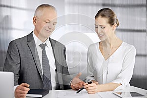 Elderly businessman and woman sitting and communicating in office. Adult business people or lawyers working together as