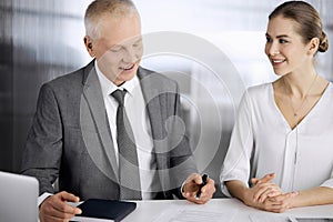 Elderly businessman and woman sitting and communicating in office. Adult business people or lawyers working together as