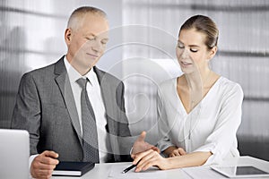 Elderly businessman and woman sitting and communicating in office. Adult business people or lawyers working together as