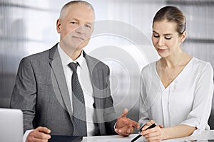 Elderly businessman and woman sitting and communicating in office. Adult business people or lawyers working together as