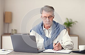 Elderly Businessman Working On Laptop Sitting In Modern Office