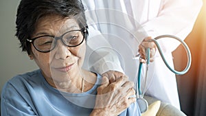 Elderly care with Asian adult senior citizen patient holding geriatric doctor, cargiving nurse or family assistant\'s hand