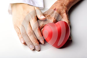 Elderly care concept, Young doctor holding senior patient hand to help and support with red heart, Family take care and nursing