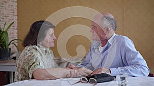 Elderly caring man checks blood pressure of his old wife with hypertension using a blood pressure monitor while sitting