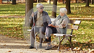 Elderly Caucasian couple sitting on the bench looking at each other in a park woman holds her husbands& x27; hands