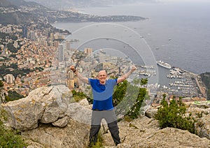 Elderly caucasian male Amerasian tourist posing on Tete de Chien, with a vew of Monaco in the background. photo