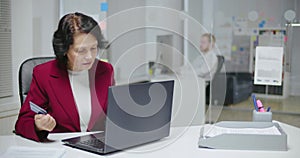 Elderly caucasian woman inputting her credit card number